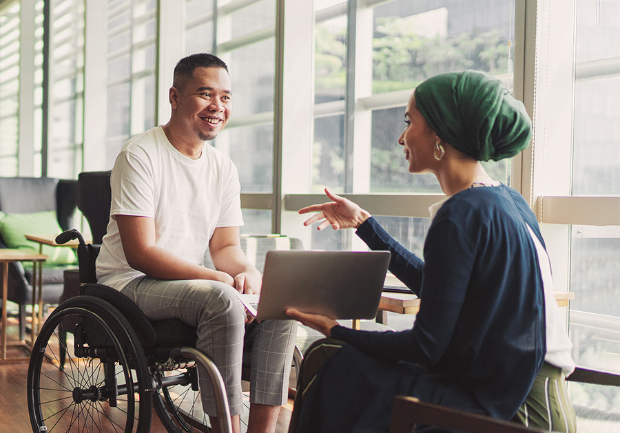 man in wheelchair chatting with woman in Hijab